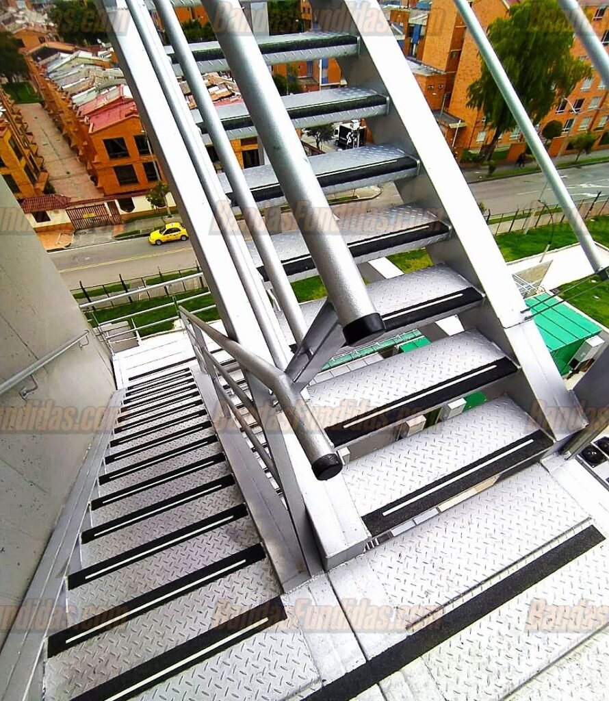 Banda antideslizante fundida instalada en escaleras de alto tráfico peatonal en Bogotá para prevención de accidentes.