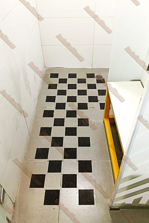 Diseño en patrón de cuadros con material antideslizante fundido en zona de vestier y baños para garantizar el cumplimiento de normativas de seguridad.