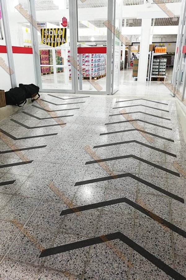 Banda antideslizante fundida instalada en rampa lisa de centro comercial para facilitar el tránsito seguro de personas y coches.