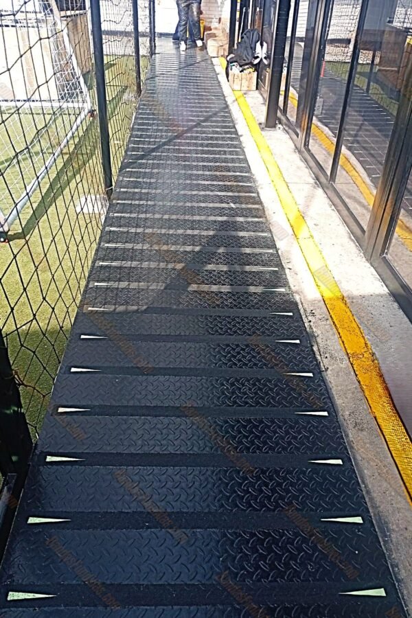Bandas fundidas antideslizantes con flechas fotoluminiscentes instaladas sobre rampas metálicas de lámina alfajor para máxima seguridad en exteriores.