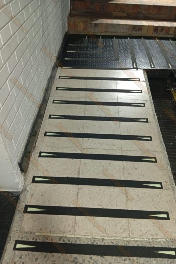 Bandas Fundidas antideslizantes con indicadores fotoluminiscentes en diseño ojo de gato aplicadas en escaleras de piedra y descansos de lámina metálica para tráfico pesado.