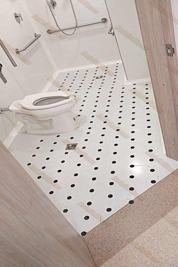 Puntos antideslizantes fundidos instalados en piso de baño para discapacitados, cumpliendo normativas de accesibilidad y prevención de caídas.